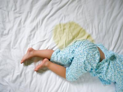 快乐美丽的宝宝独自站在尿布里尿床: 孩子的床垫,小女孩的脚和尿在床