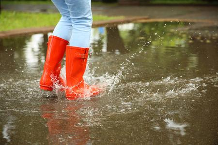 雨天雨靴穿惠灵顿靴的小男孩一个小男孩在水坑里跳.