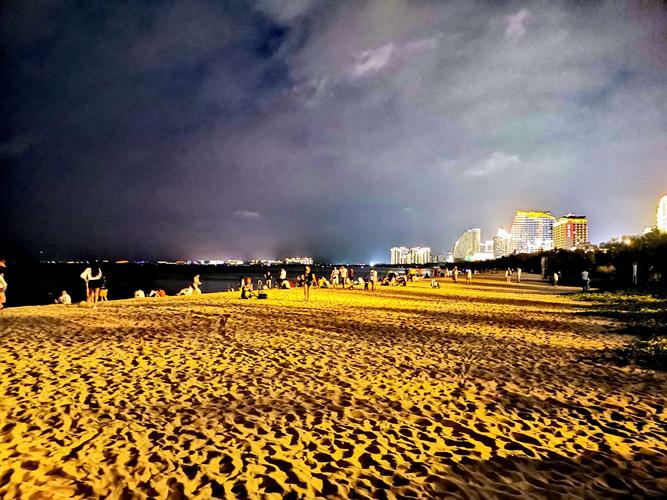 三亚湾夜晚的沙滩上大人和 三亚湾美丽的夜景看远方 金黄色的灯光