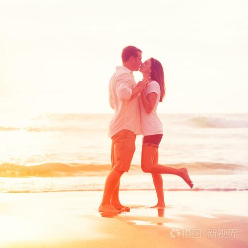 浪漫的情侣在沙滩上亲吻日落时分