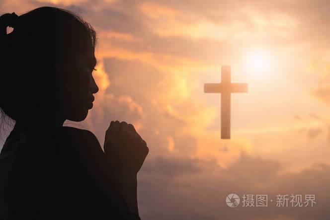 年轻女子在日出时用十字架祈祷的剪影,基督教的概念背景.