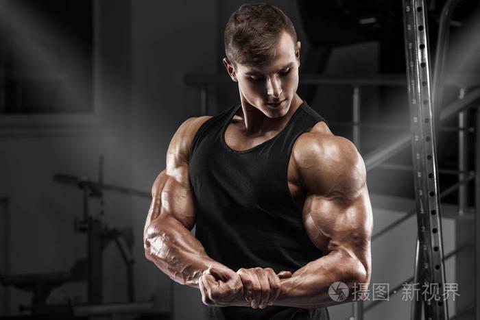 肌肉男在健身房锻炼.强壮的男性显示肌肉肱二头肌
