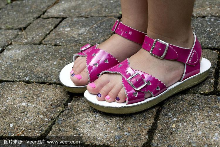 小女孩的脚上涂着五颜六色的趾甲,穿着粉红色的凉鞋