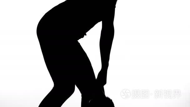 在一个白色的背景, 一个影子, 一个女性身材的黑色轮廓做练习做重量