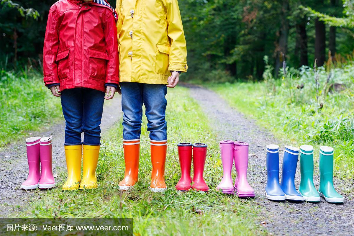 小孩子,男孩和女孩穿着五颜六色的雨靴.孩子们站在秋天的森林里.