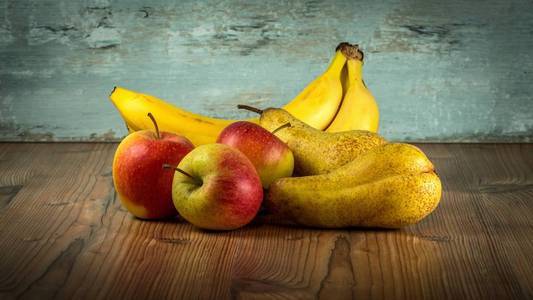 苹果,梨和香蕉放在乡村的木桌上.平静的生活.照片