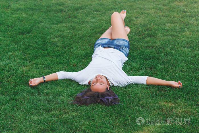 快乐的女人穿着躺在草地上
