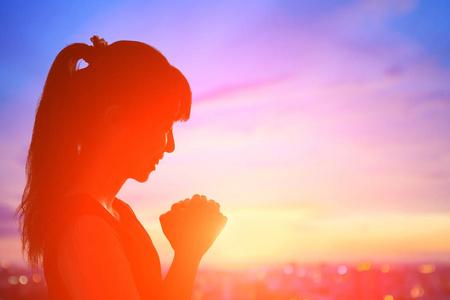 年轻女子在日出中祈祷照片
