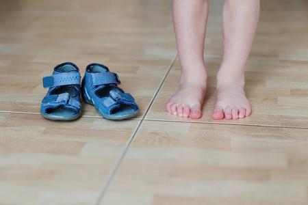 婴儿赤脚和拖鞋在地板上棕色的鞋鞋柜与儿童鞋不同的衣服的小女孩儿童