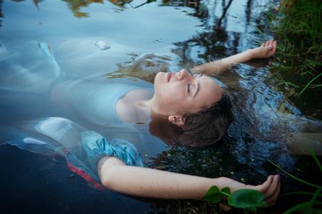 年轻美女穿着蓝色的衣服躺在河里淹死照片