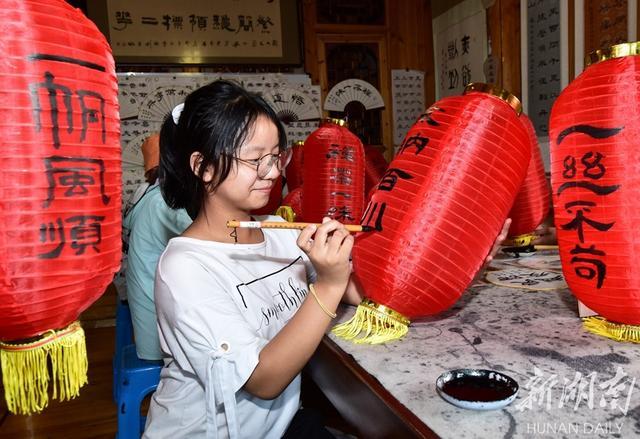 8月8日,吉首市石家冲街道寨阳村,孩子们在红灯笼上进行书法创作.