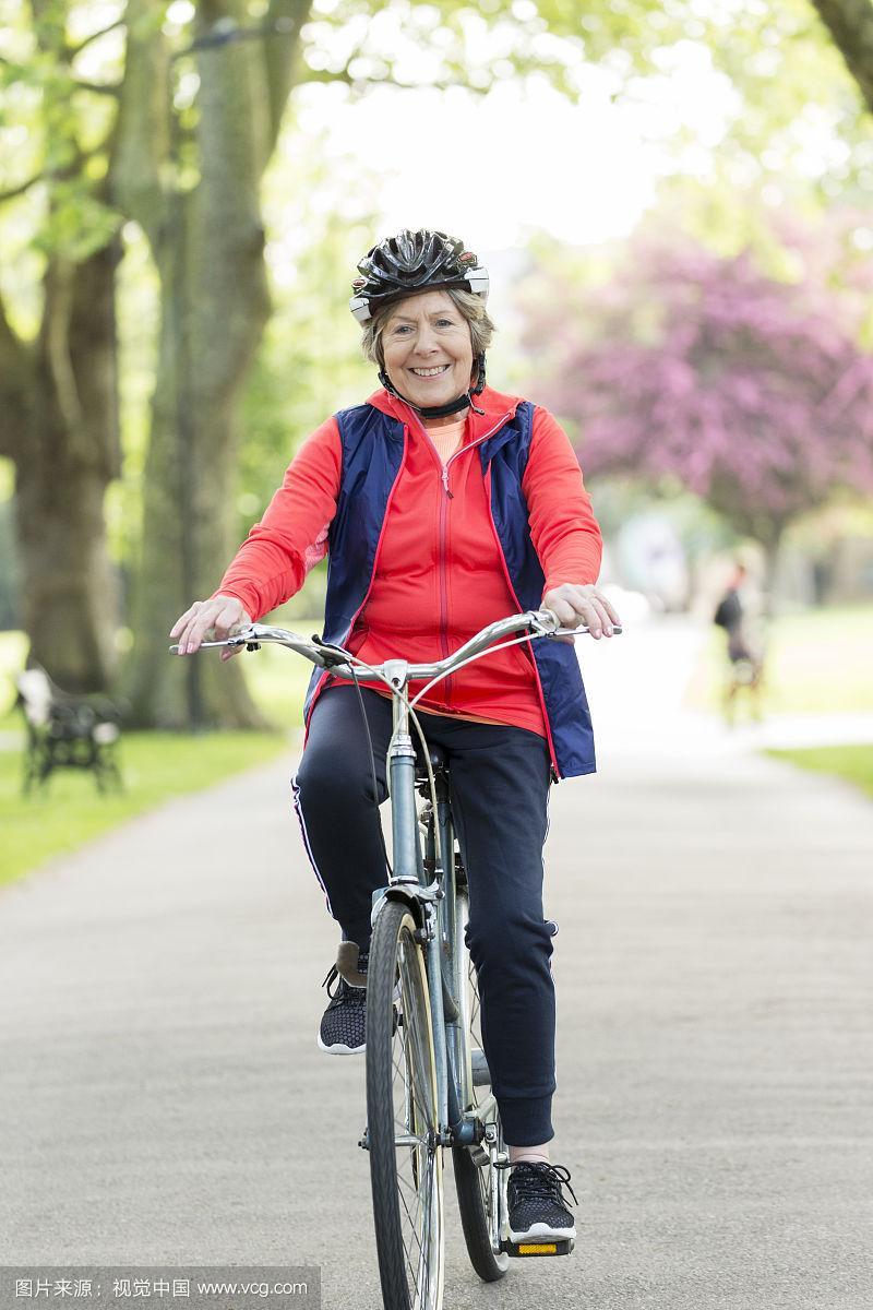 肖像活跃的老年妇女在公园骑自行车