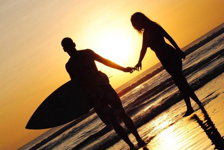 黄色户外温馨夕阳下海边牵手的情侣背景图片