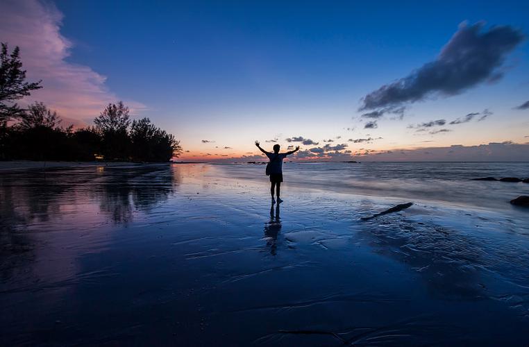 日落时分,一个人站在海滩上图片