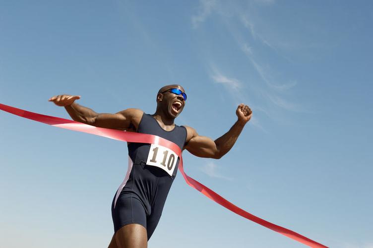 一位非裔美国男子赛跑运动员在蓝天赛跑中获胜的低角度观察