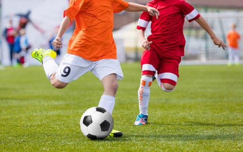 男孩跑和踢足球.青少年足球足球比赛照片
