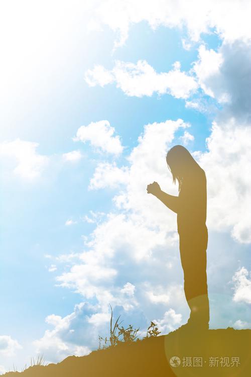 女人在美丽的天空背景下祈祷的剪影