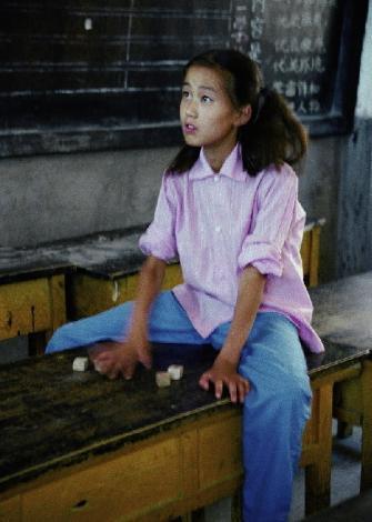 80年代中国历史老照片:图为一个扎着两个马尾辫的小女孩坐在教室的
