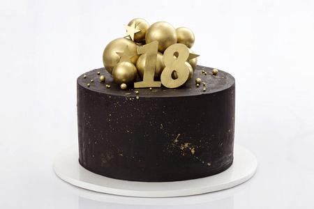 黑色巧克力蛋糕饰以金色的球巧克力在白色的背景.生日蛋糕18岁照片