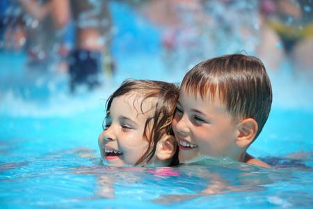 露天豪华游泳池微笑的男孩和小女孩在水上公园的游泳池里游泳照片