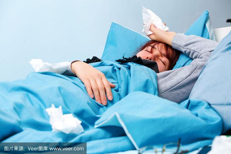 病床上躺着一个拿着纸巾的生病妇女的照片