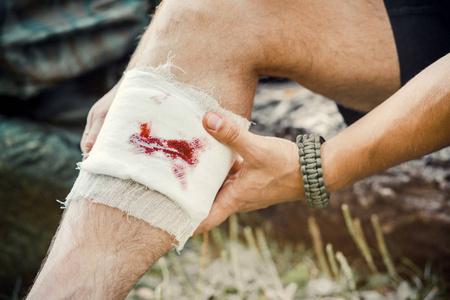 脚伤口包扎一个年轻人,一个游客,用绷带包扎伤口照片