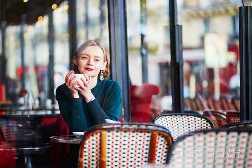 法国巴黎传统咖啡馆里喝咖啡的年轻优雅的女人
