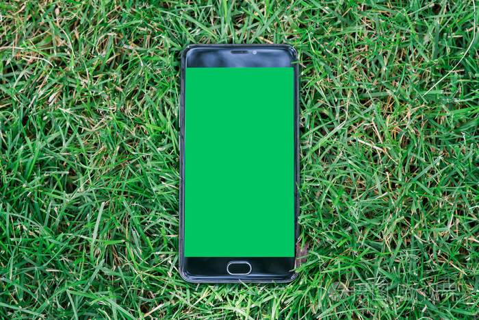 绿屏的关键色度屏幕的特写智能手机.绿草背景