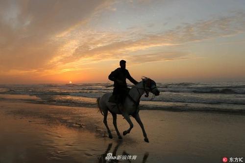 当地时间2018年1月3日,巴勒斯坦,加沙少年海边骑马,夕阳映衬分外妖娆