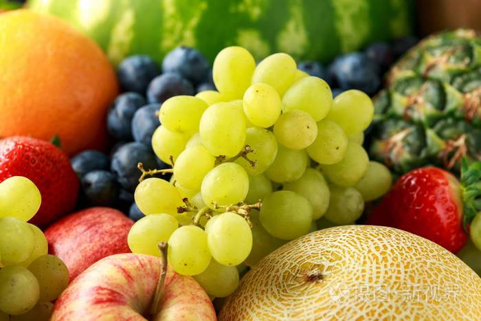 深色背景的各种新鲜水果和浆果:哈密瓜,甜瓜,西瓜,蓝莓,橘子,苹果