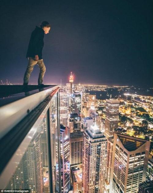 年轻人为俯瞰城市 坐摩天大楼边缘拍照