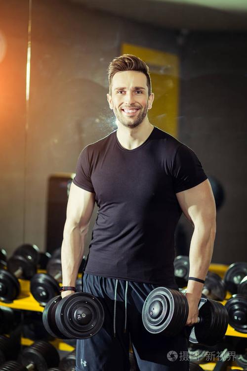 健康生活方式运动强壮的肌肉男在健身房锻炼,用哑铃锻炼二头肌照片