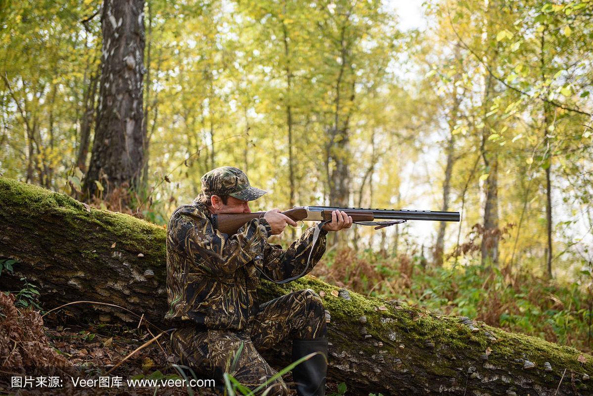 猎人带着枪在秋天的树林里