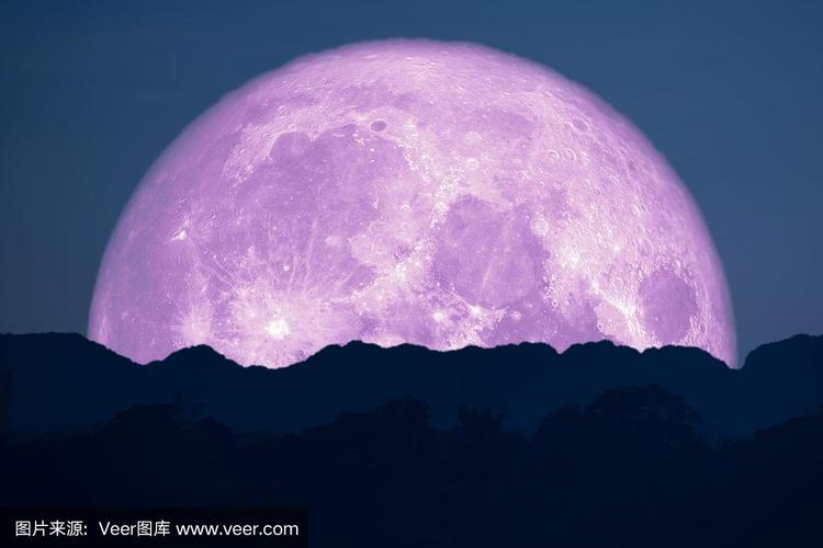在夜空中,粉红色的月亮回到了山的轮廓上