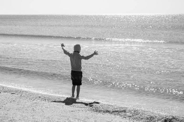 快乐的小男孩跑步和跳跃在海浪中在黑海海滩上