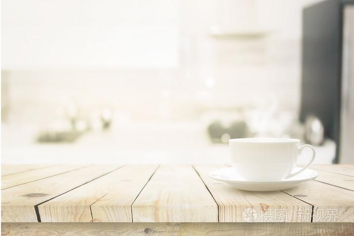 木制的桌子在模糊厨房室内背景上的白色杯