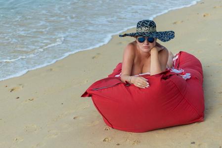 水面女人女人赤身裸体,戴着白帽子,戴着墨镜,躺在靠近水面的红色床垫