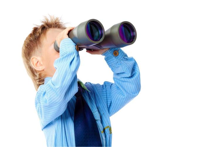 大未来,好奇的小男孩正在通过双筒望远镜.孤立在白色背景.