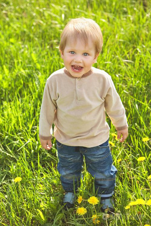 绿色草地上快乐的童年户外金发小男孩