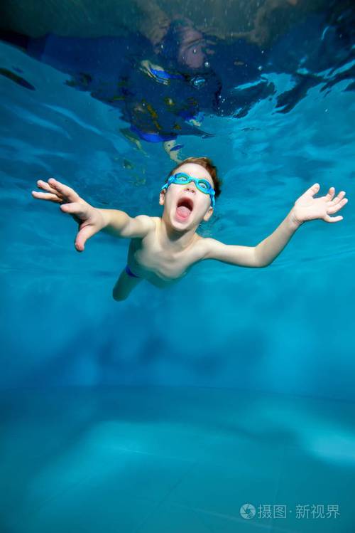 照片 小男孩在水下游泳,靠近水面.像鸟一样张开双臂.