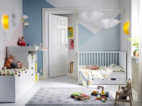 儿童卧室内放着一张白色婴儿床,双层抽屉,婴儿换衣桌和带脚轮储物式长