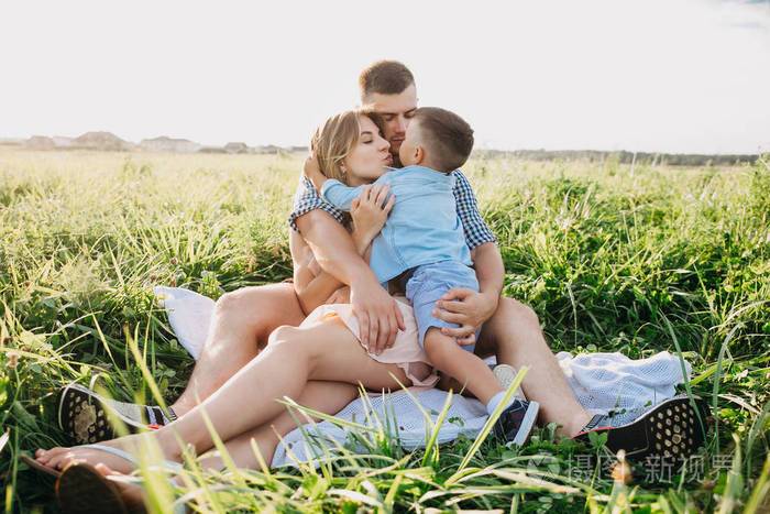在阳光明媚的夏日里一家人坐在草地上拥抱