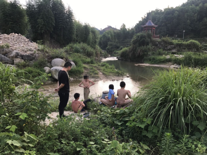 一采砂河段有几名小学生结伴在河里游泳.