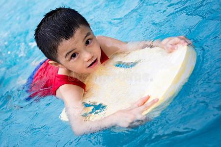 游泳用肩胛骨亚洲中国小男孩用浮板游泳照片