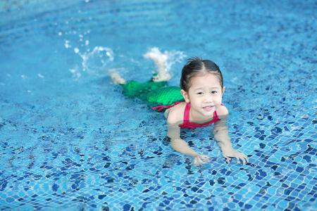 可爱的亚洲小女孩的肖像,穿着美人鱼泳衣,在游泳池里玩得很开心.照片