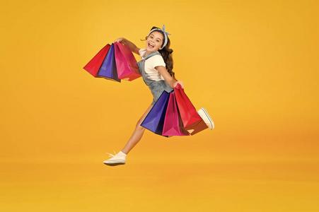快乐的女孩拿着购物袋跳起来.小孩子拿着纸袋微笑.假期准备和庆祝.