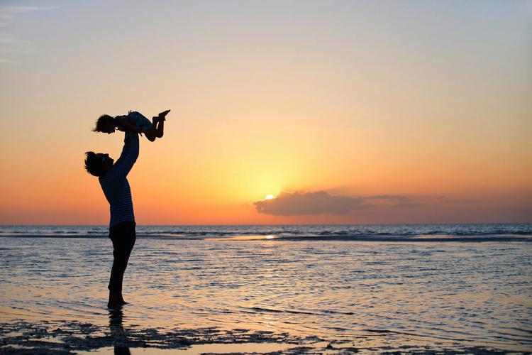 日落时父亲和小女儿在海滩上的轮廓幸福童年 幸福孩子美好童年